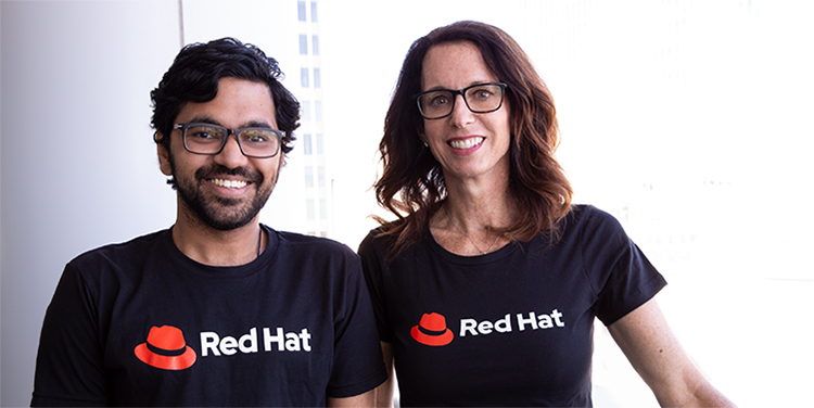 Two people wearing black t-shirts with the Red Hat logo on the chest.